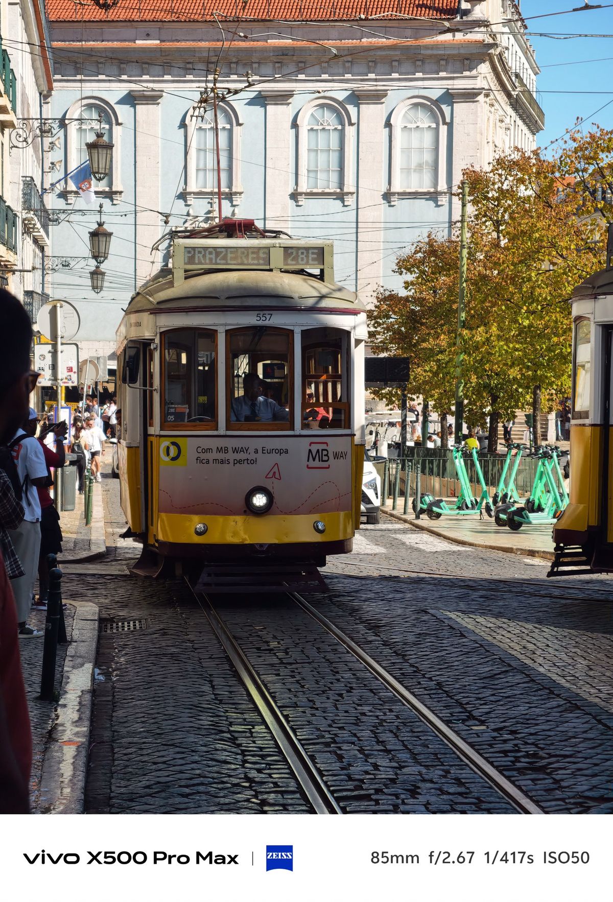 Lisbon tram marked 28E Prazeres approaching along cobbled tracks.