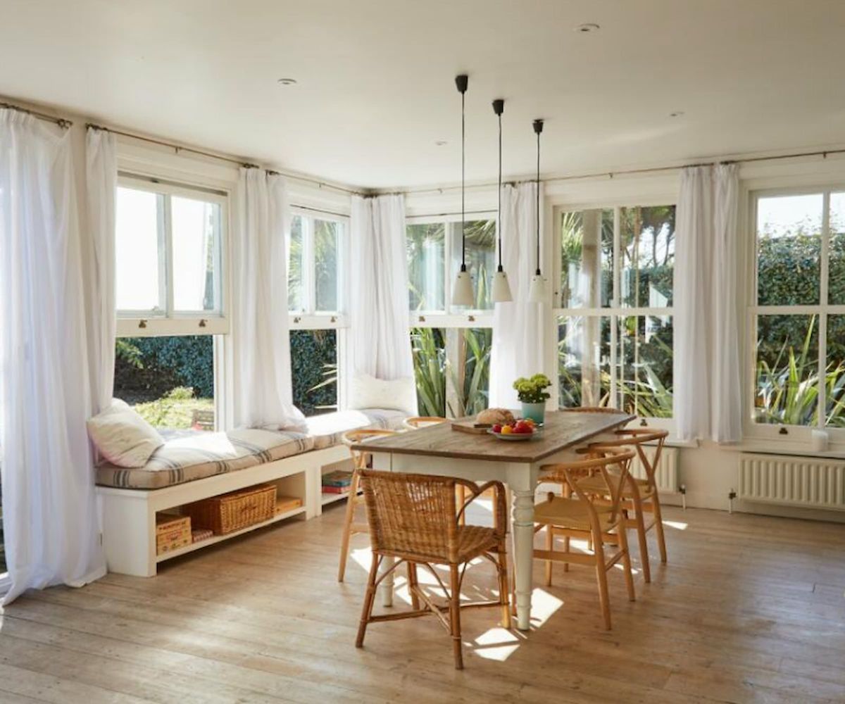 A dining room with window balcony seats and wooden dining table