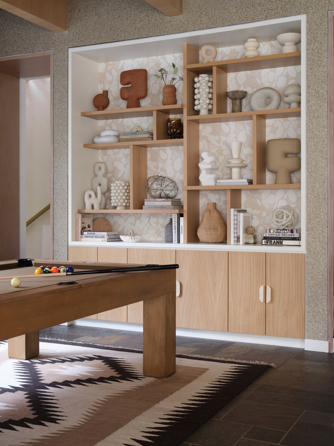 a bookshelf wall with varying decor items in light tan colors