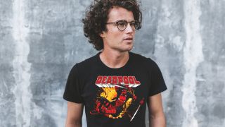 White man with brown curly hair and classes wearing a Deadpool T-shirt
