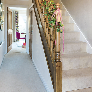 hallway with white wall and stairs with wooden railing
