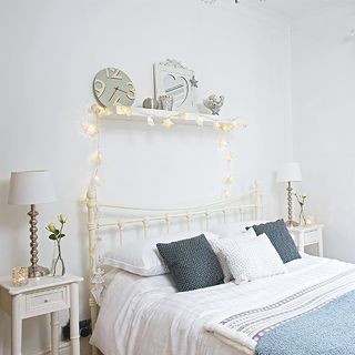 bedroom with white wall white shelf on wall and white bed with cushion