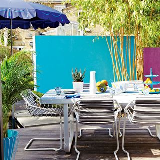 decking area with blue feature wall rectangular plastic table and garden chairs