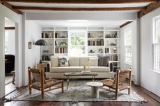 White sitting room with white sofa, woven rug and woven chairs