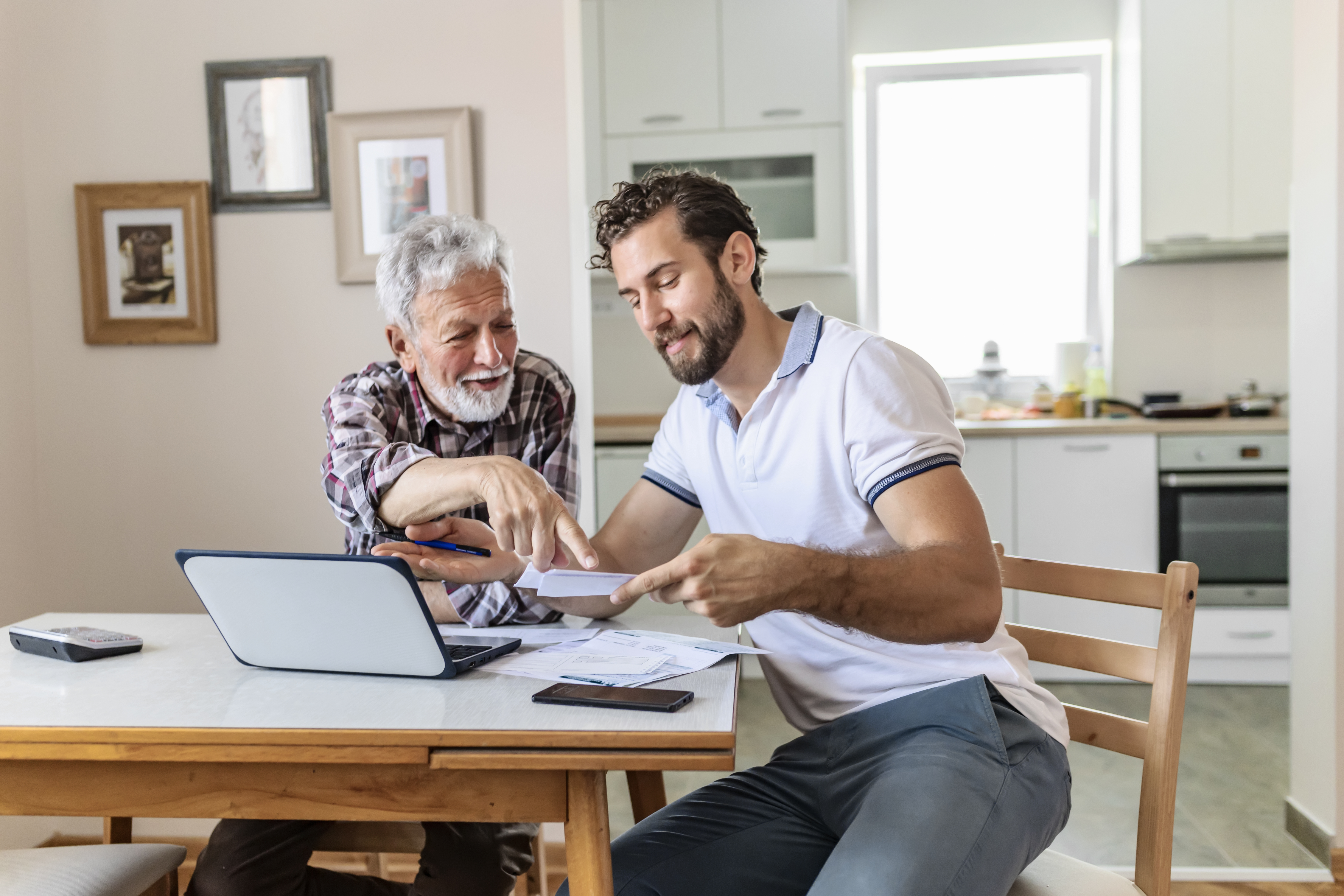Son Giving Senior Parent Financial Advice at Home. Adult Son Doing Accounts Together With His Senior Father at Home, Planning New Purchase. Family Budget and Finances.