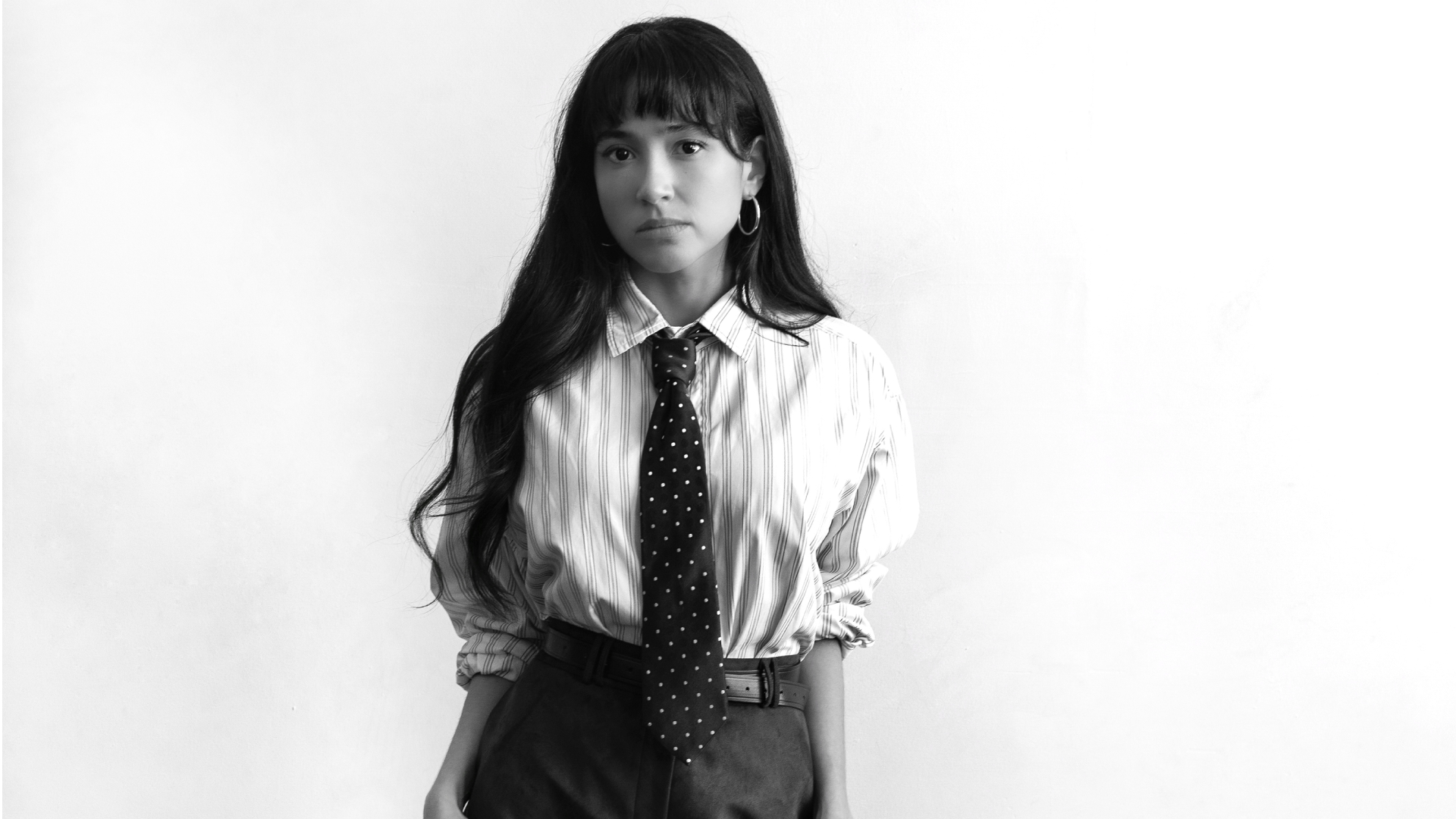 actress and comedian wally baram poses in a button down and polka dot tie in a black and white press shot