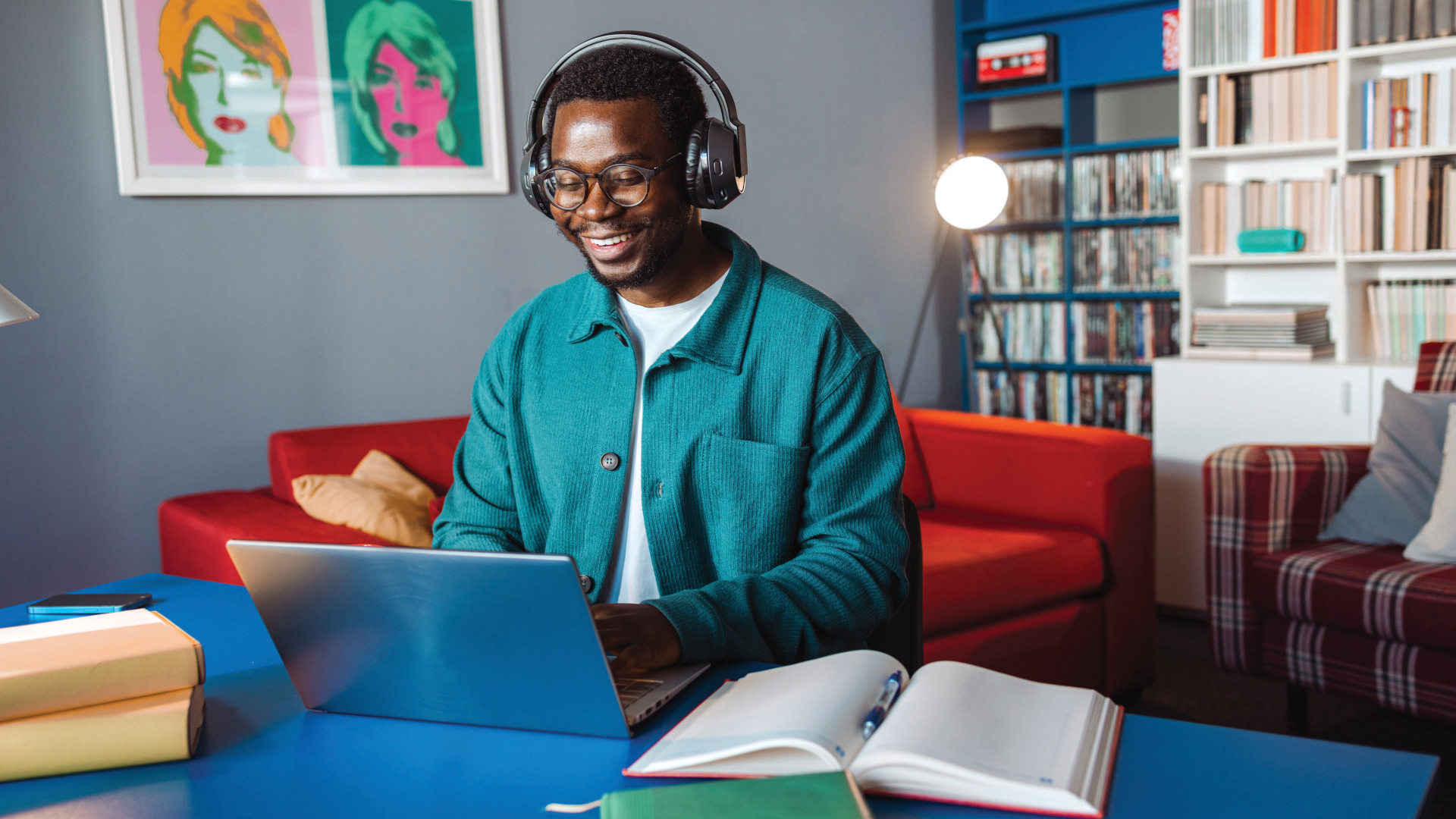 Young person looking happy wearing headphones at a laptop in their living room at home
