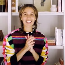 Cleo Wade smiling and standing in front of her bookshelves
