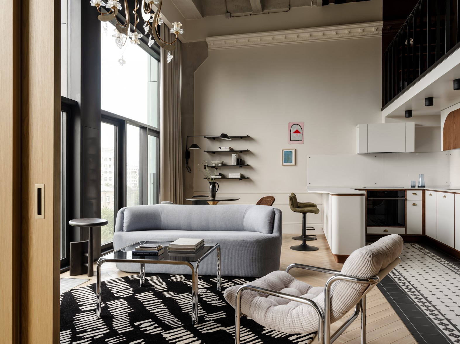 A spacious living room with white walls, a black and white rug, and gray furniture.