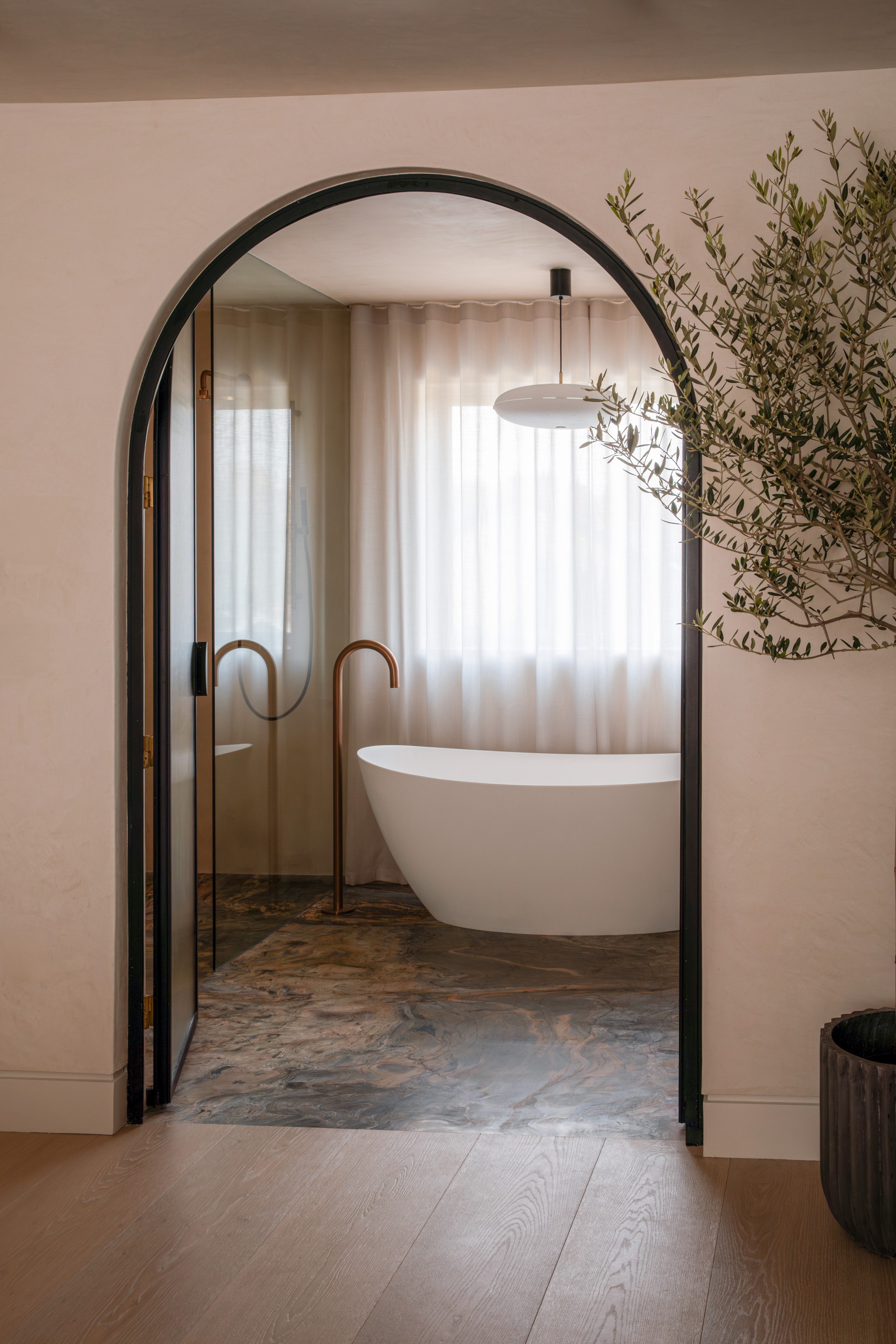 Bathroom with arched entrance and curved freestanding bath