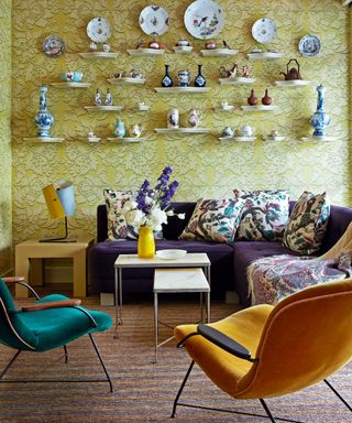 colorful living room with Meissen pottery, yellow patterned wallpaper, purple sofa and yellow chair