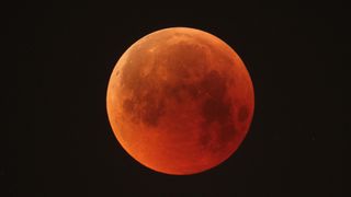 The moon appears to be a rusty red color in this image of a lunar eclipse.