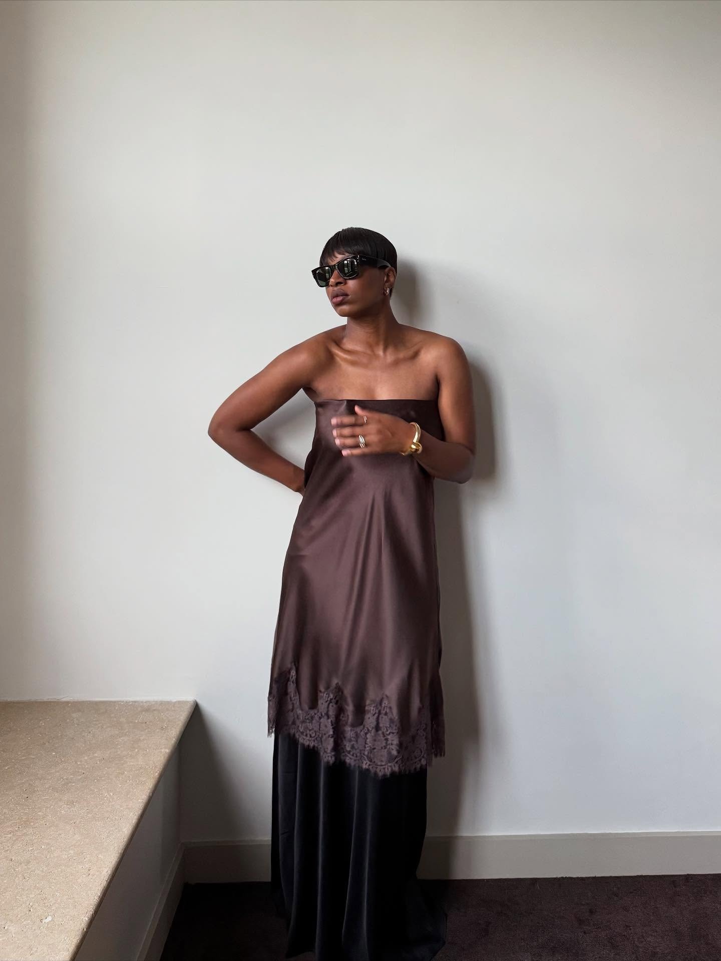 A woman in a brown silky co-ord with a stylish pixie haircut