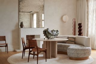 A dining area with circular table, curved seating and neutral decor