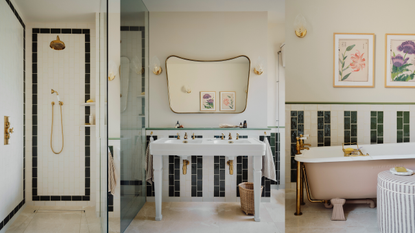 a striped black and white tiled bathroom with a pink free standing bath and a double sink