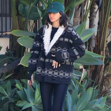 Bruna Marquezine wears black leggings with a shearling-trimmed jacket and a ralph lauren hat.