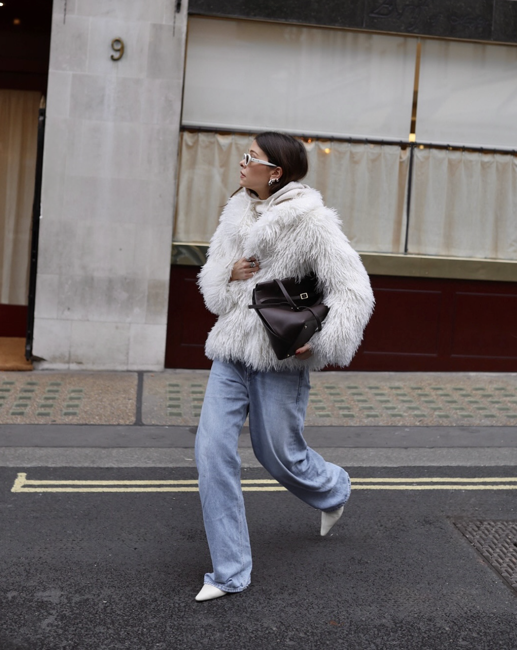 woman in light wash jeans and a shaggy white fur coat