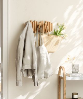 Wooden hooks on neutral wall with jacket and bags