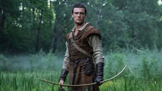 Jack Patten holds a bow standing in a field
