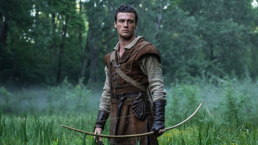 Jack Patten holds a bow standing in a field