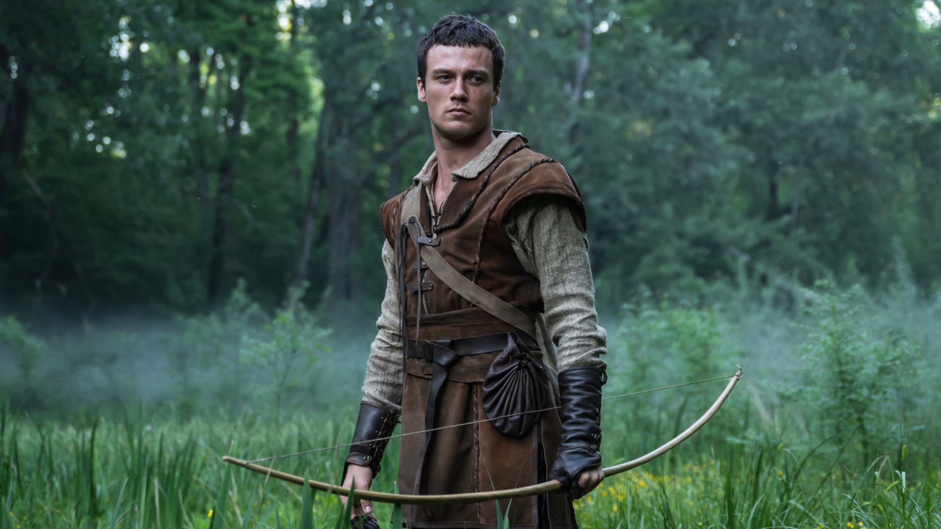 Jack Patten holds a bow standing in a field