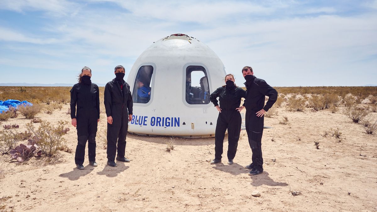 Blue Origin personnel standing in as astronauts during Mission NS-15 pose in front of the New Shepard Crew Capsule after a successful mission on April 14, 2021.