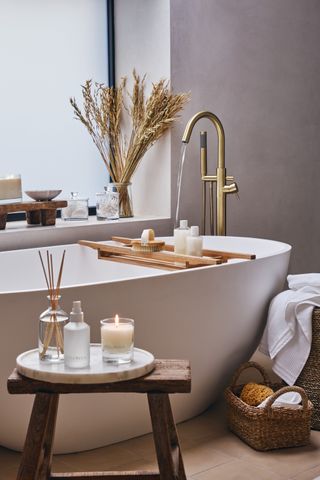 white small bathroom with rustic stool and jute wicker baskets by The White Company