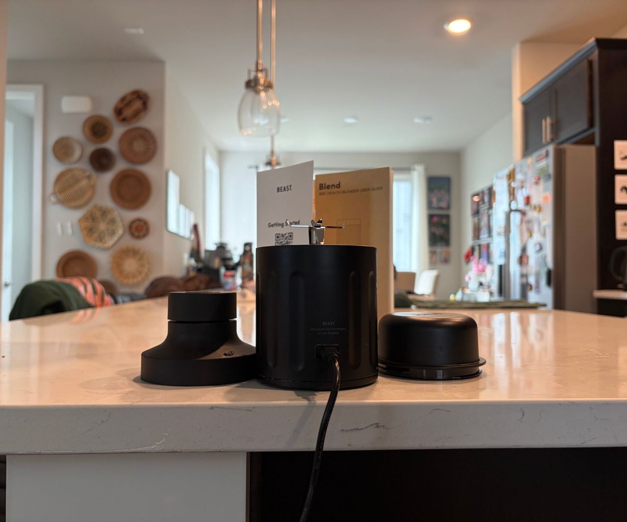 The black blade base and lid from the Beast GO portable blender on a white kitchen counter.