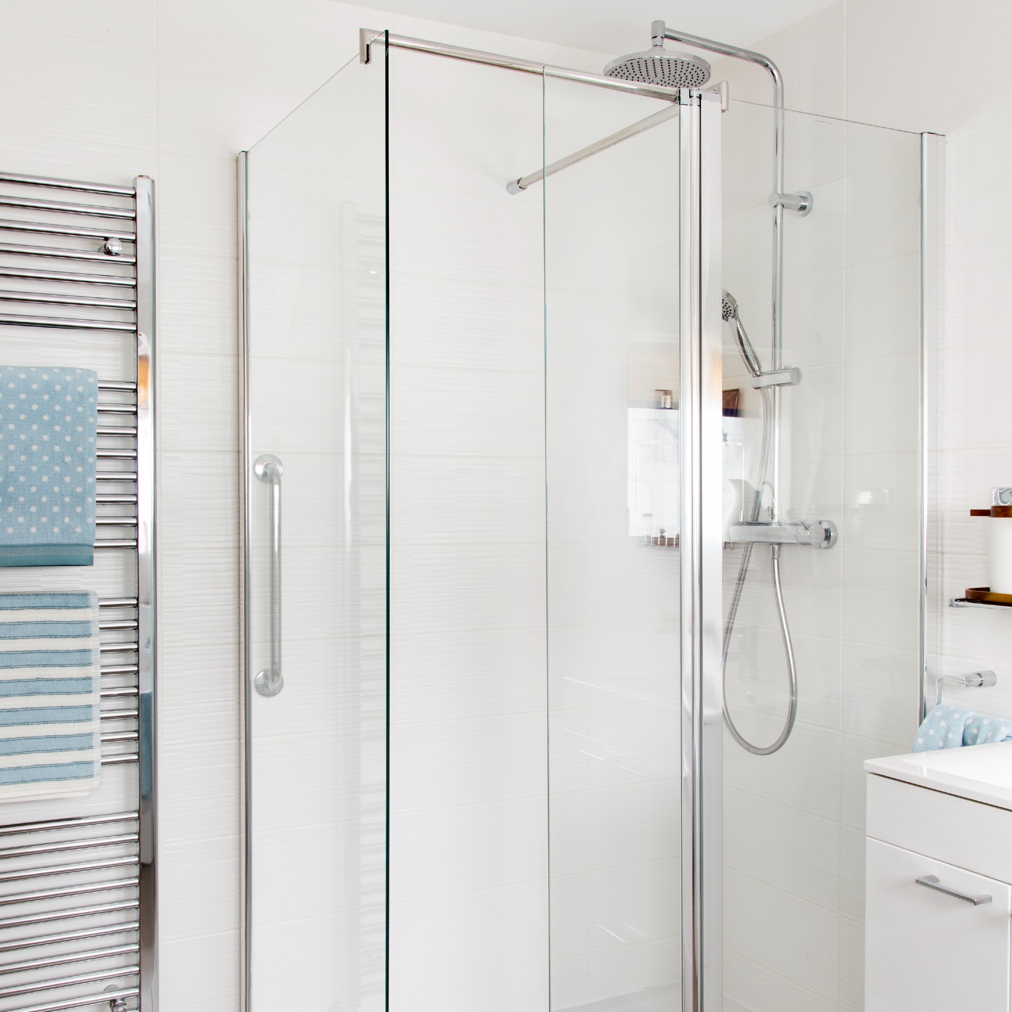 A white bathroom with a shower and glass shower screen