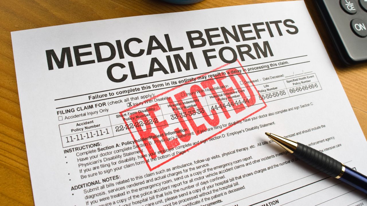 Medical benefits claim form sitting on a desk with a red &quot;rejected&quot; stamp