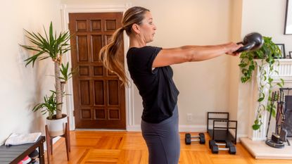 Woman performing kettlebell swing at home