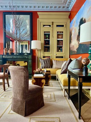 A living room with a home library shelf painted yellow in contrast to the red walls