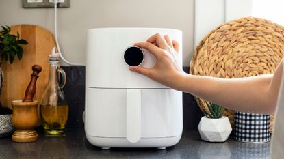 A white air fryer plugged in on a kitchen side