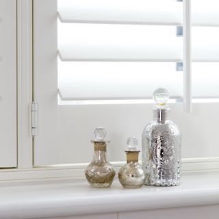 A window with Venetian blinds and beauty products on the windowsill