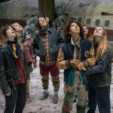 the yellowjackets look up at the sky during winter time around a crash plane in the wilderness in the final season of the series
