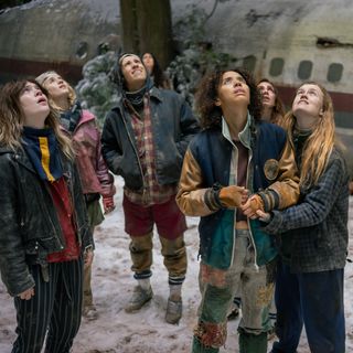 the yellowjackets look up at the sky during winter time around a crash plane in the wilderness in the final season of the series