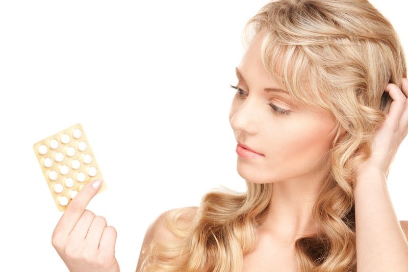 A woman holds a pack of birth control pills