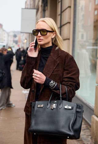 a street-style photo of a woman carrying a Hermés bag in a story about how to buy an hermés bag