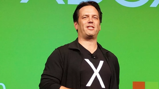 Phil Spencer giving a talk on stage, wearing a t-shirt with an 'X' on it.