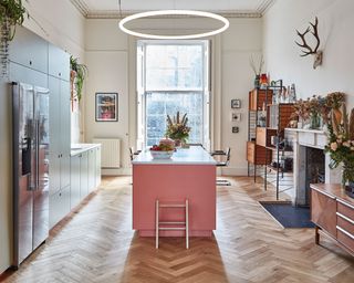 Kitchen with pink island and overhead pendant light