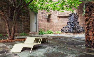 Paved courtyard with tree, water fountain and aluminum lounger