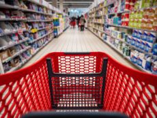 Personal perspective of a shopper pushing shopping cart along aisle while shopping in a supermarket.