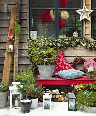 Christmas porch decor ideas with a bench decked with cushions and a potted Christmas tree