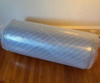 The Siena Memory Foam Mattress in plastic wrap on the floor.