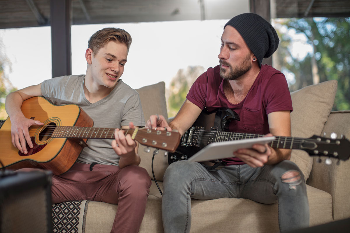 Man teaches student how to play guitar