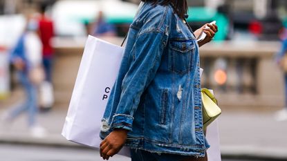woman in denim jacket carrying shopping bags