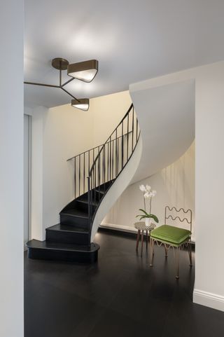 A stairwell with a modern curved staircase with black stairs