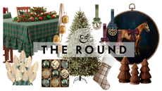 "Ralph Lauren Christmas"-style holiday decor, including a plaid tablecloth, string lights, ornaments, brass bells, a faux pre-lit tree, plaid stocking, rattan decorative tree group, and equestrian art