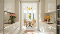 A light glossy galley kitchen leading to a sunny dining are with cane chairs