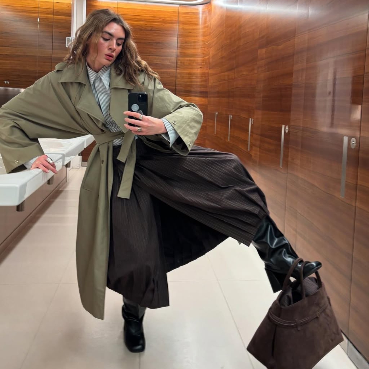 kat from finance in her work bathroom with a brown suede bag